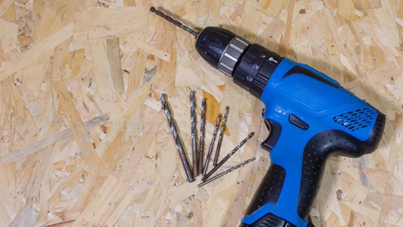 Impact driver vs drill - Close up of electric drill and drill bits on old wooden table