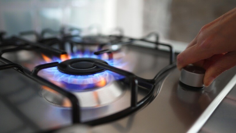 Gas vs electric range - A person turning on their gas range