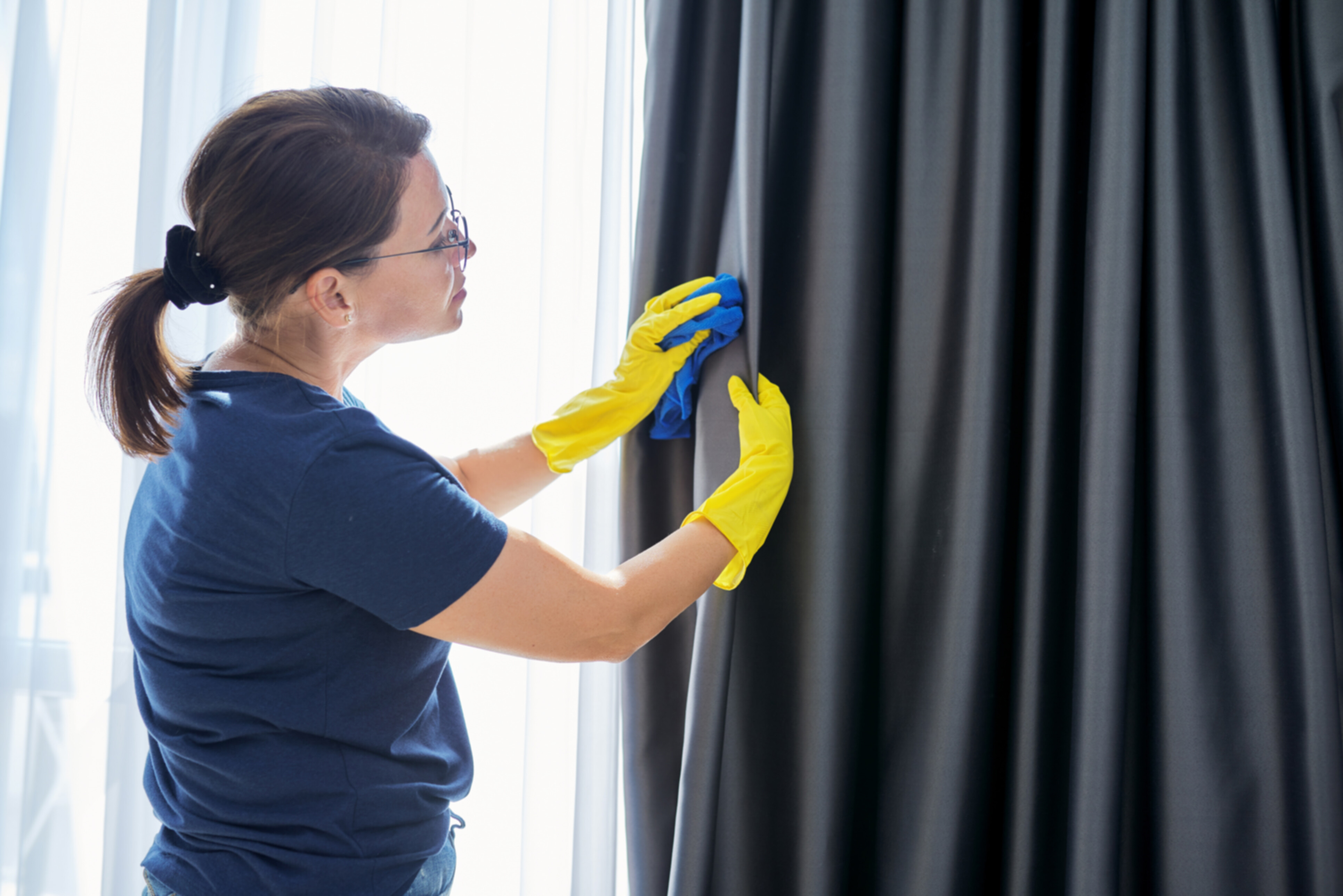 A professional cleaner wiping off a curtain.