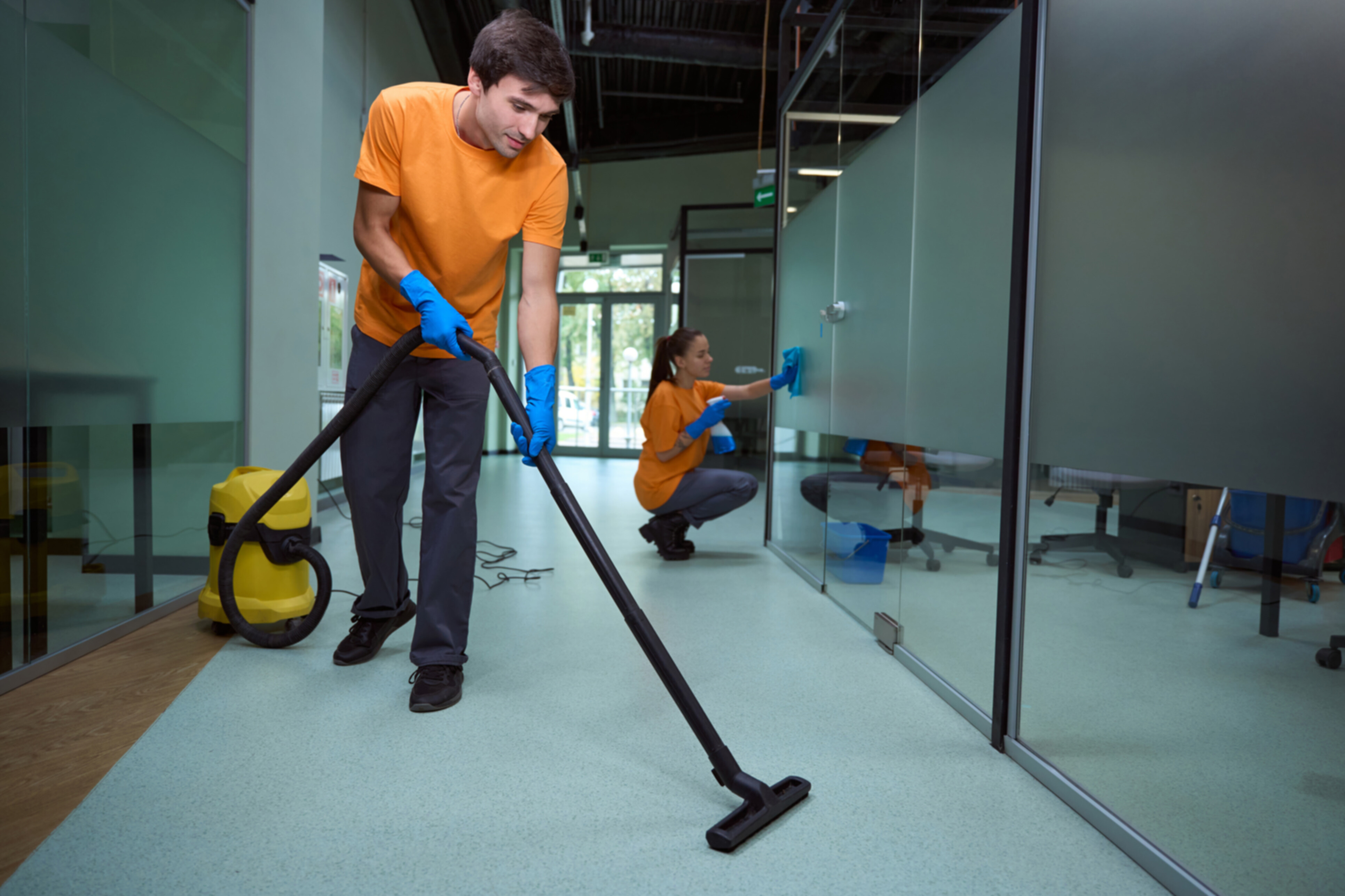 A pair of commercial cleaners tidying up an office space.