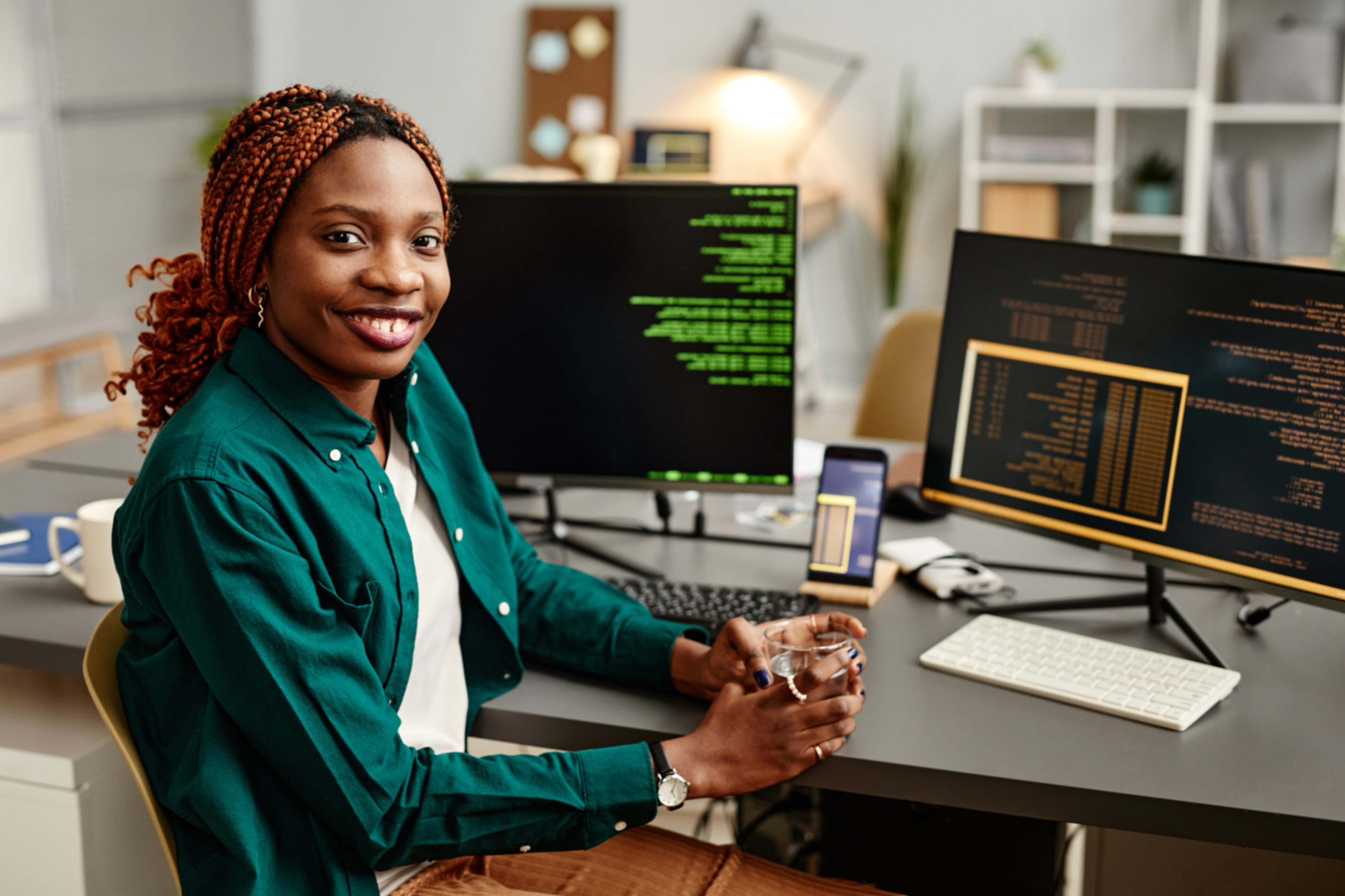 An african american female PHP developer posing in front of her workspace.