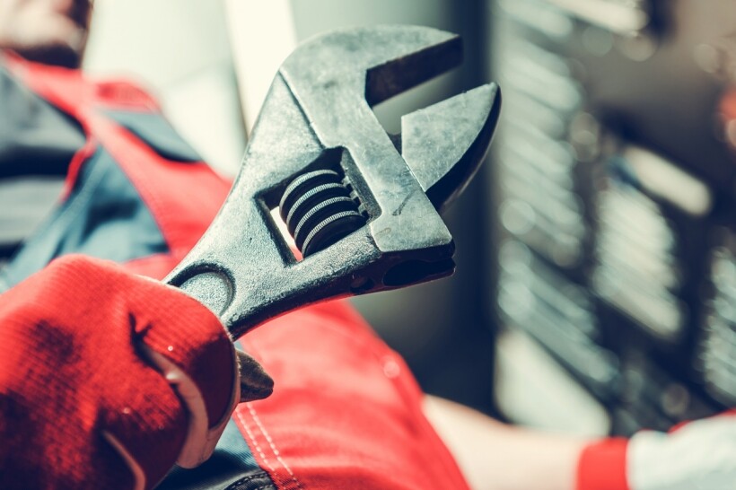 Spanner vs wrench - A man holding an adjustable wrench.