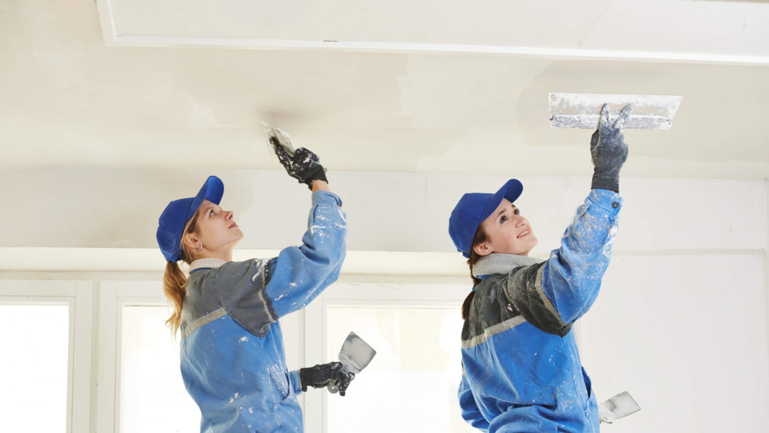 Skimming vs plastering - Plasterers smoothing a new plaster ceiling for a home renovation