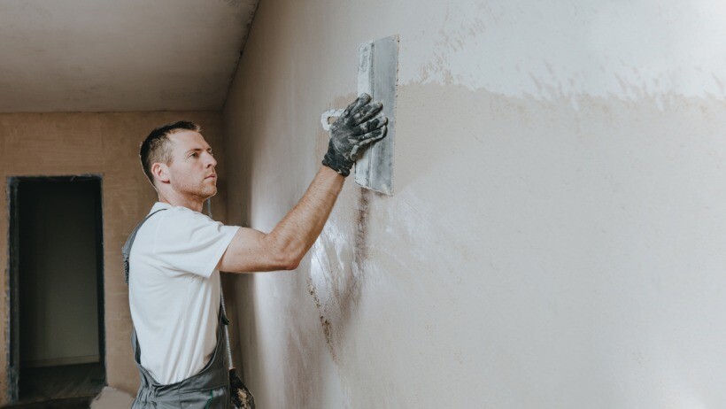 Plastering vs skimming - A professional plastering a wall using a construction trowel