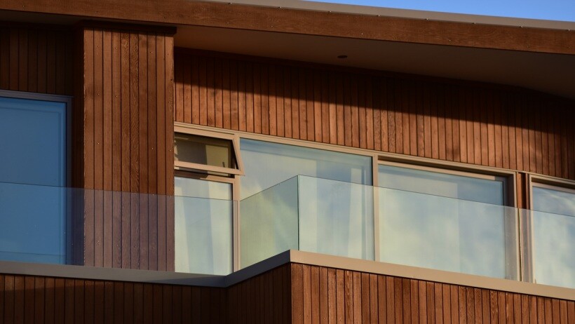 Wall cladding vs wall panelling - Modern house with vertical wood cladding, glass railing, and large windows on the facade