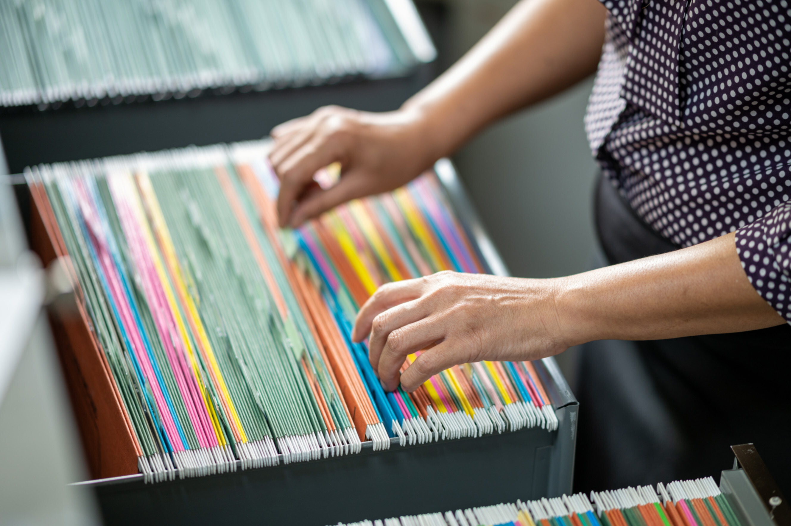 Document filer near me organises colourful files in a cabinet and sorts through folders for efficient document management.