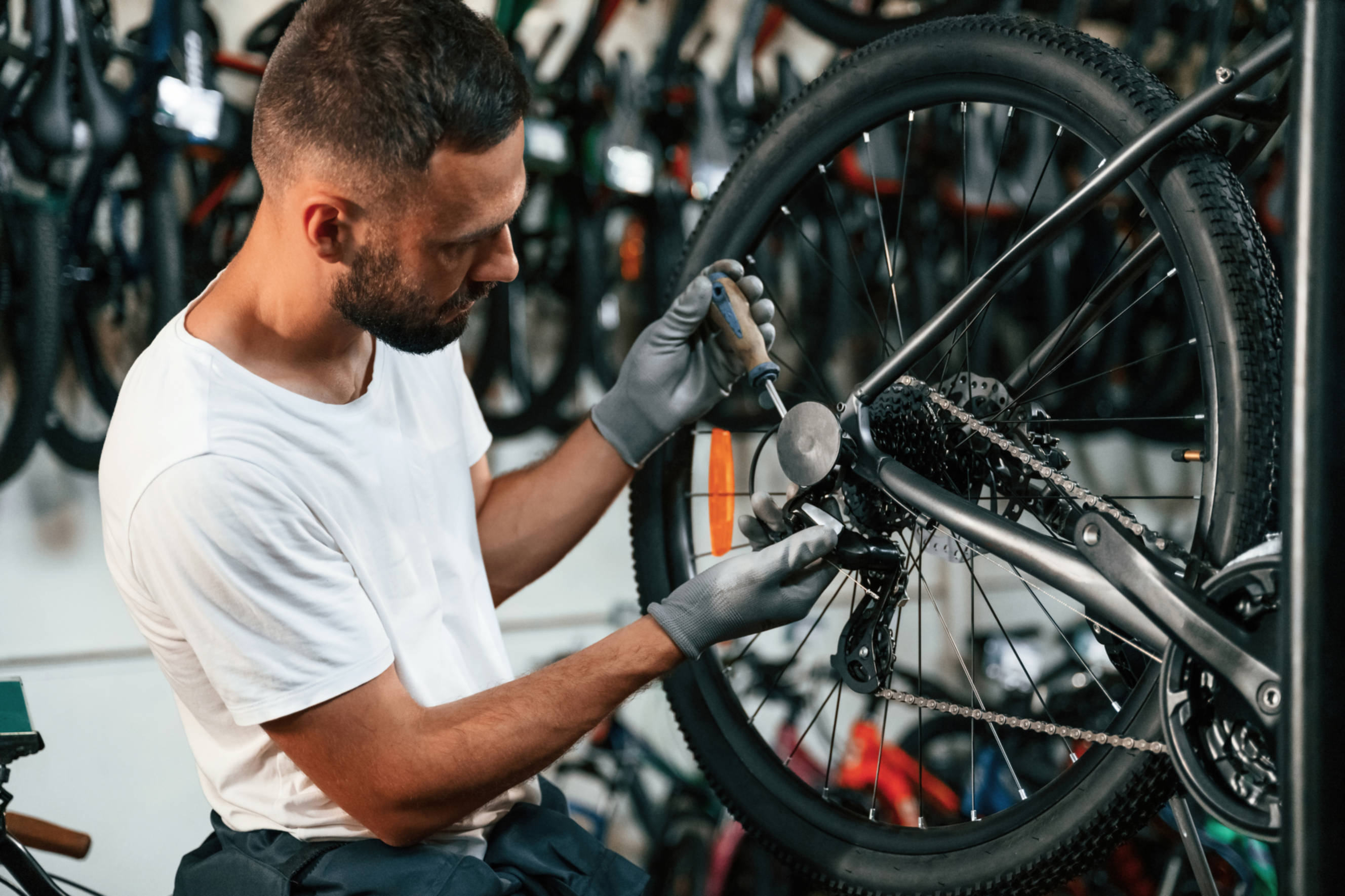 Mechanic performing a bicycle tyre repair, fixing the rear wheel of a bike in a workshop to ensure proper function and safety.