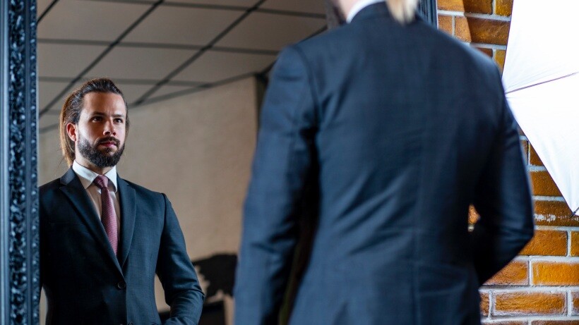 Tailored fit vs slim fit - A well-dressed person in a slim fit navy blue suit standing in a tailor's showroom