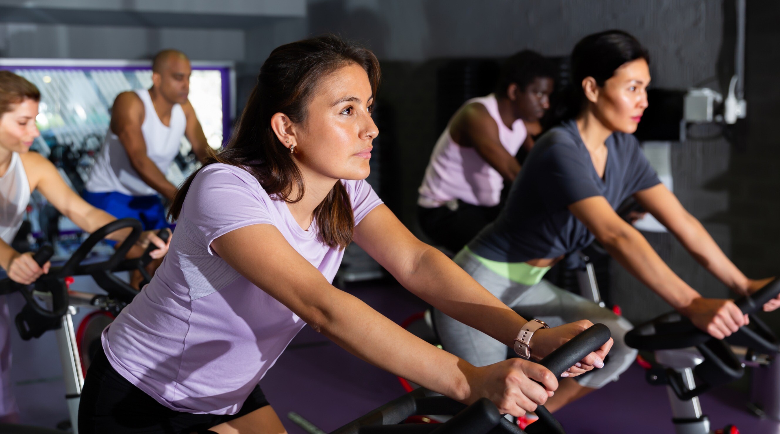 A group of people engaged in a cycling training session at a gym.