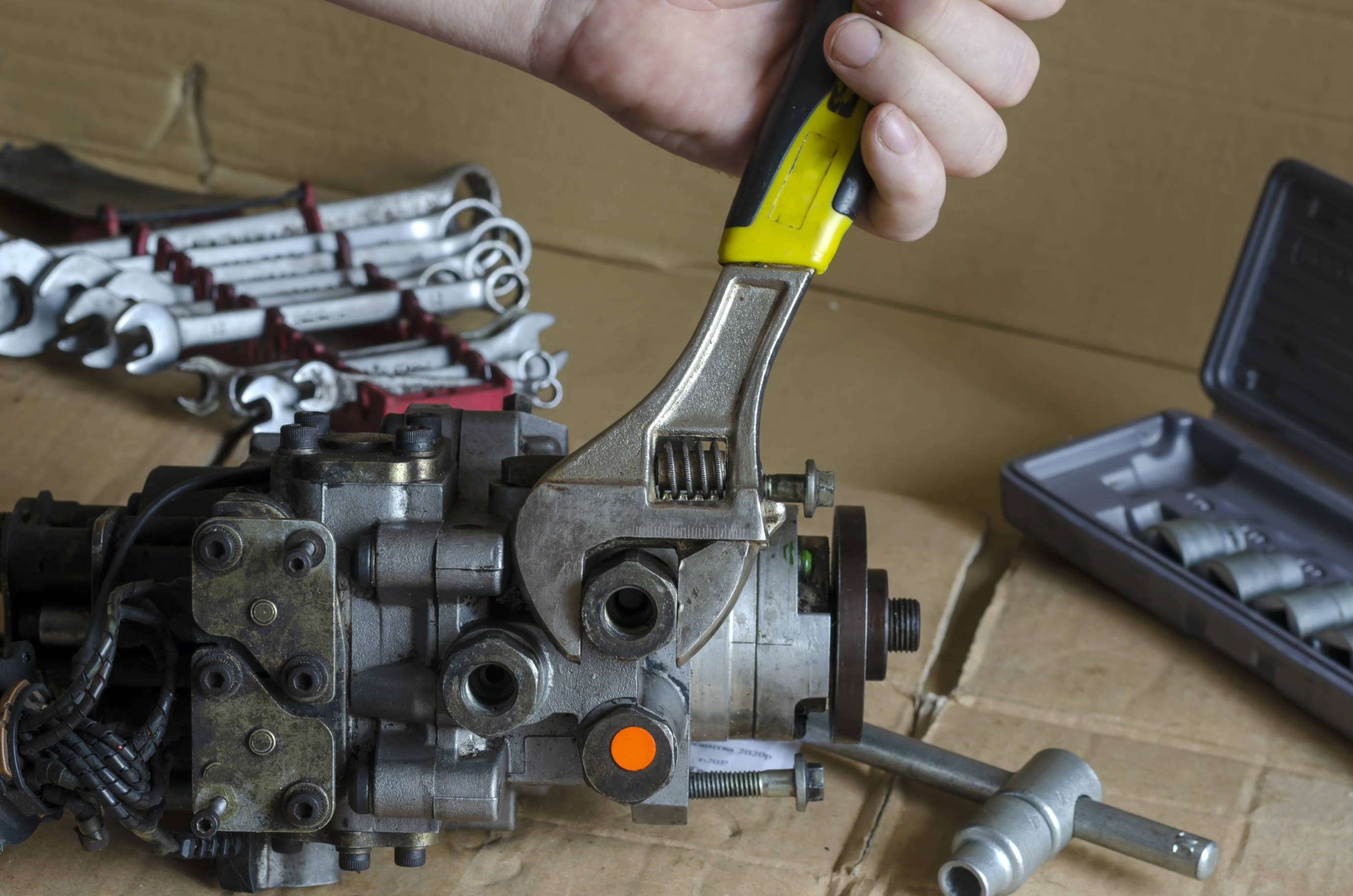 Mechanic using a wrench to adjust a fuel pump to prepare for a car fuel pump replacement.