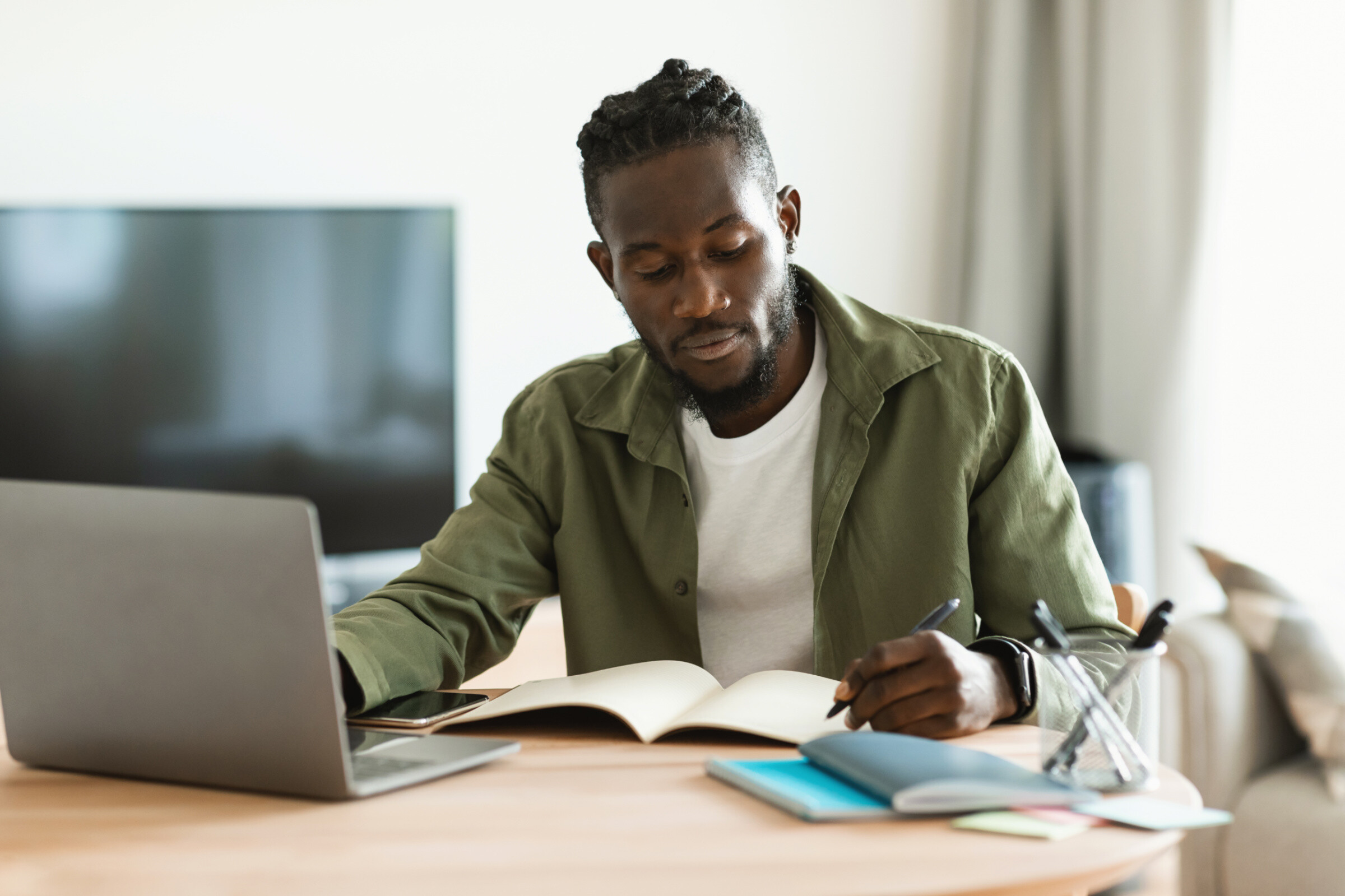 A professional website tester taking notes while working on his macbook.