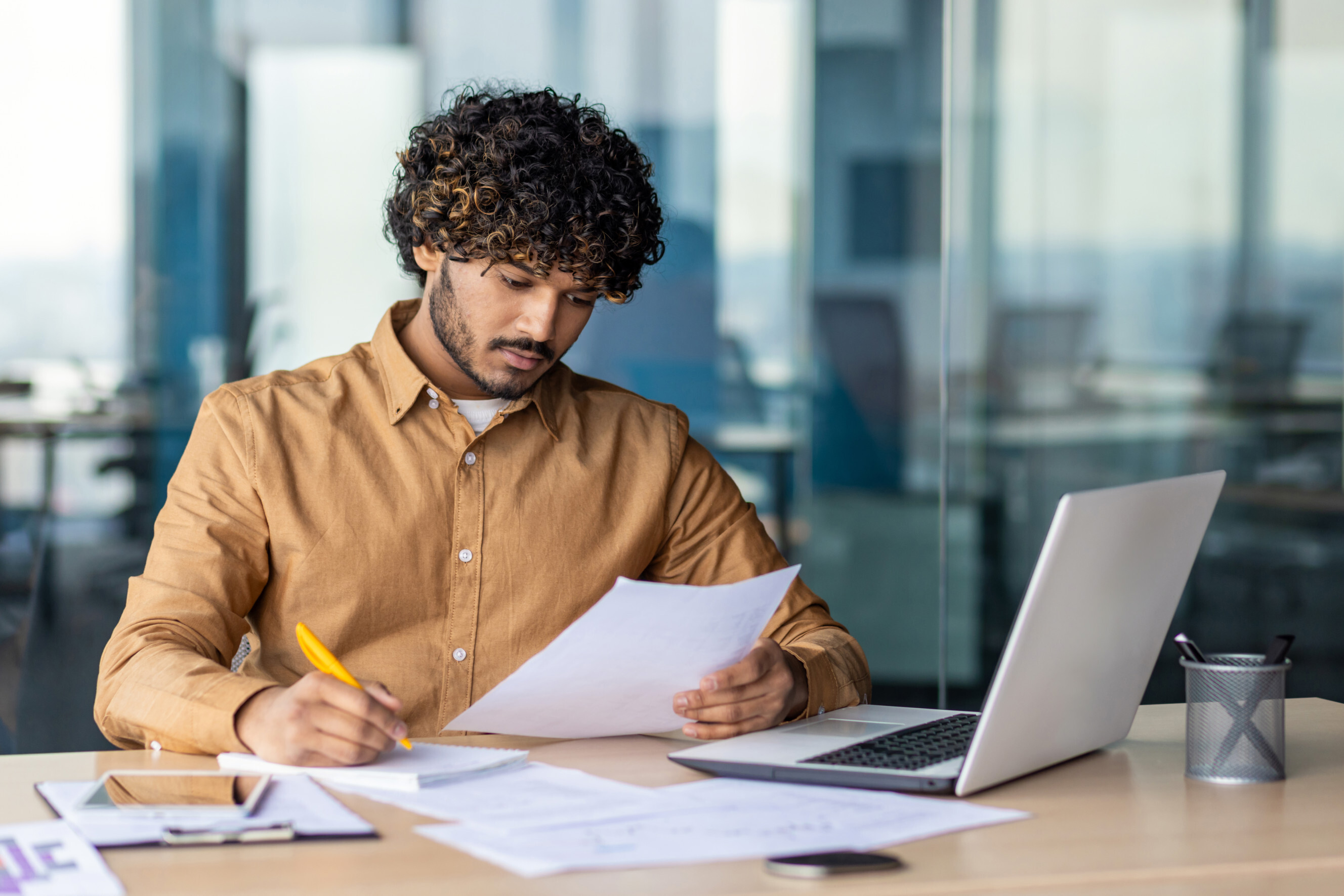 Hispanic man reviewing contract reports and invoices for copywriting.