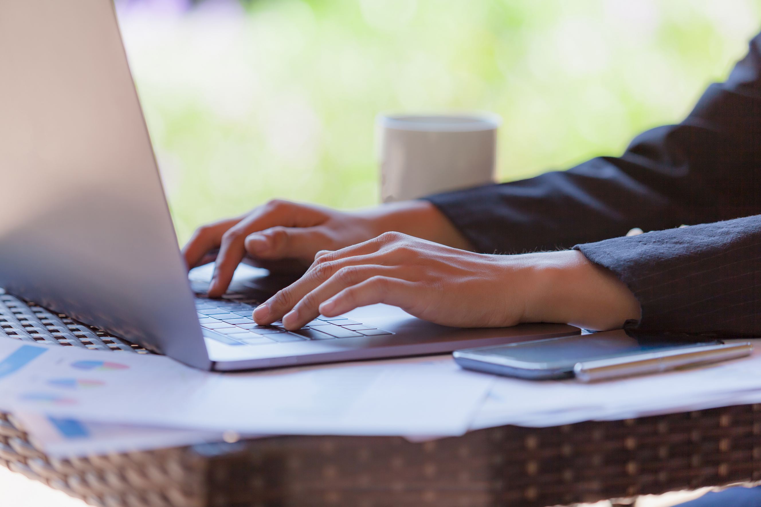 A young businesswoman using a laptop for her proposal writing task while sitting in a modern cafe.