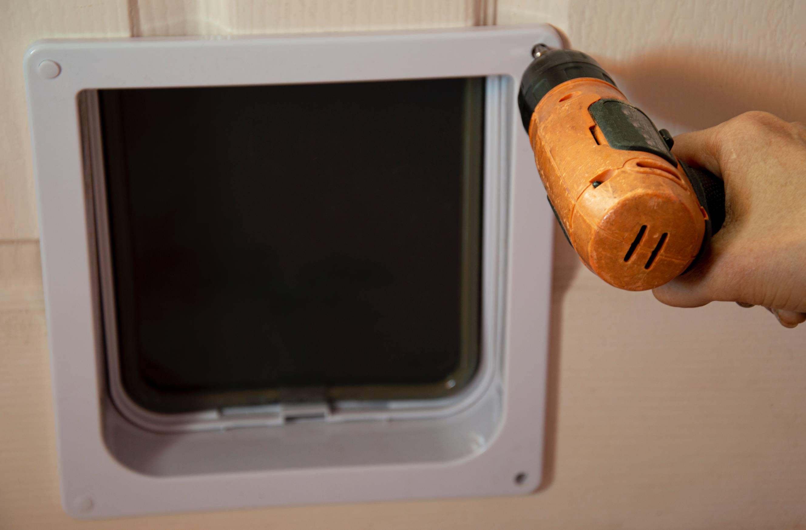 A handyman installing a dog door for pets in a home.