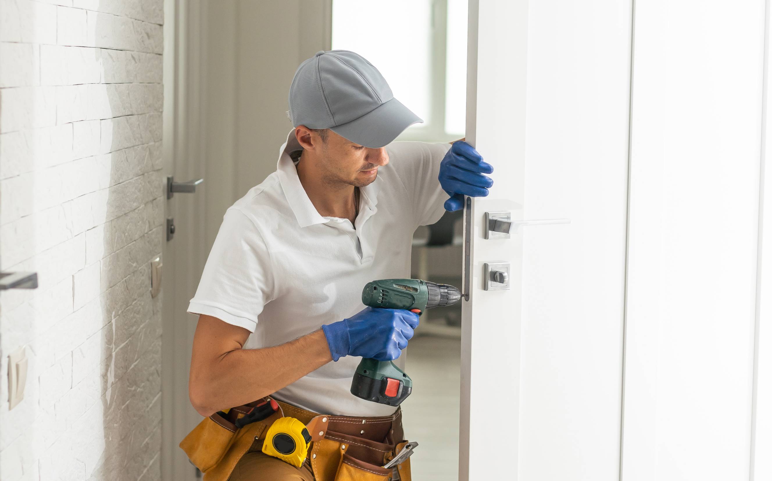 A handyman is using a power tool during a door repair service for a home.