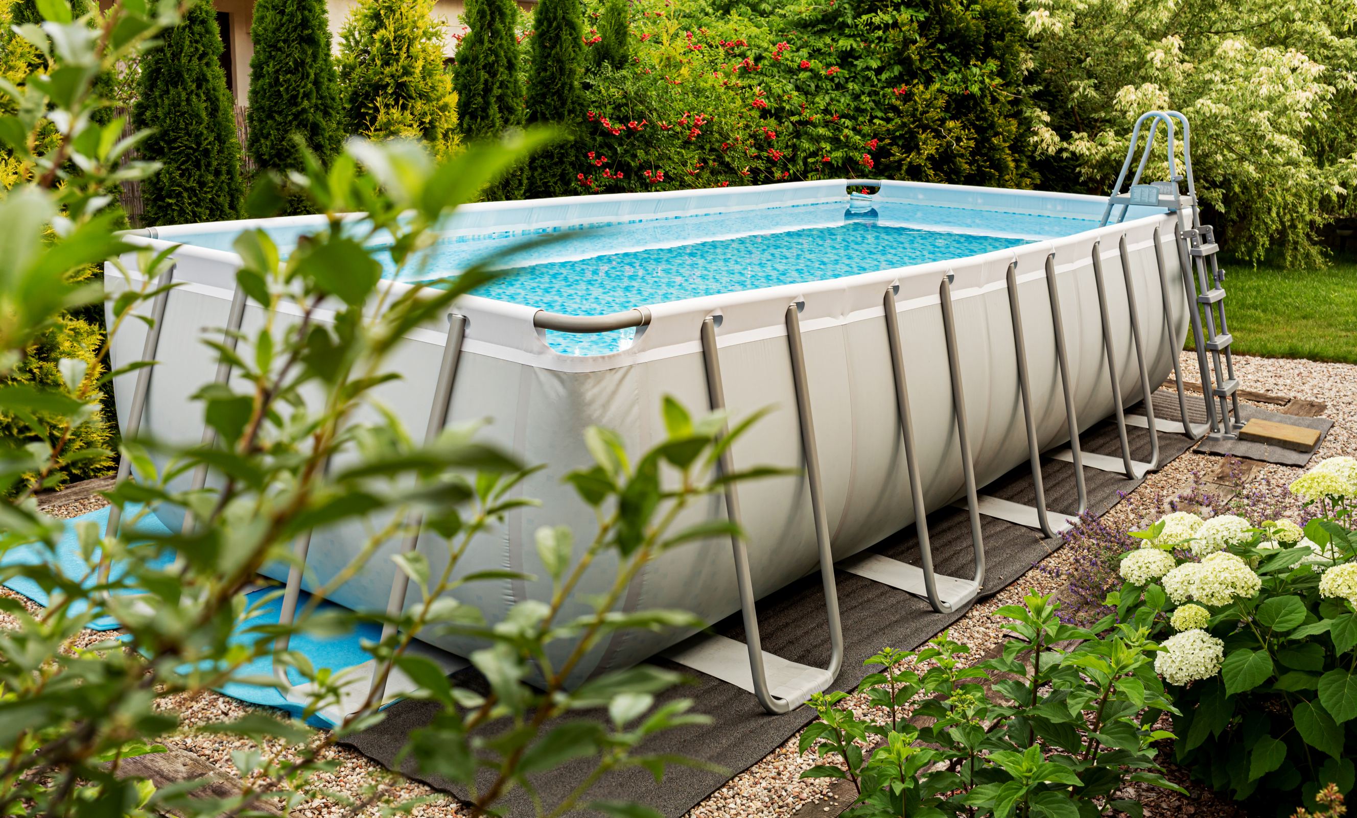 Long rectangular, above-ground pool outdoors in the garden.