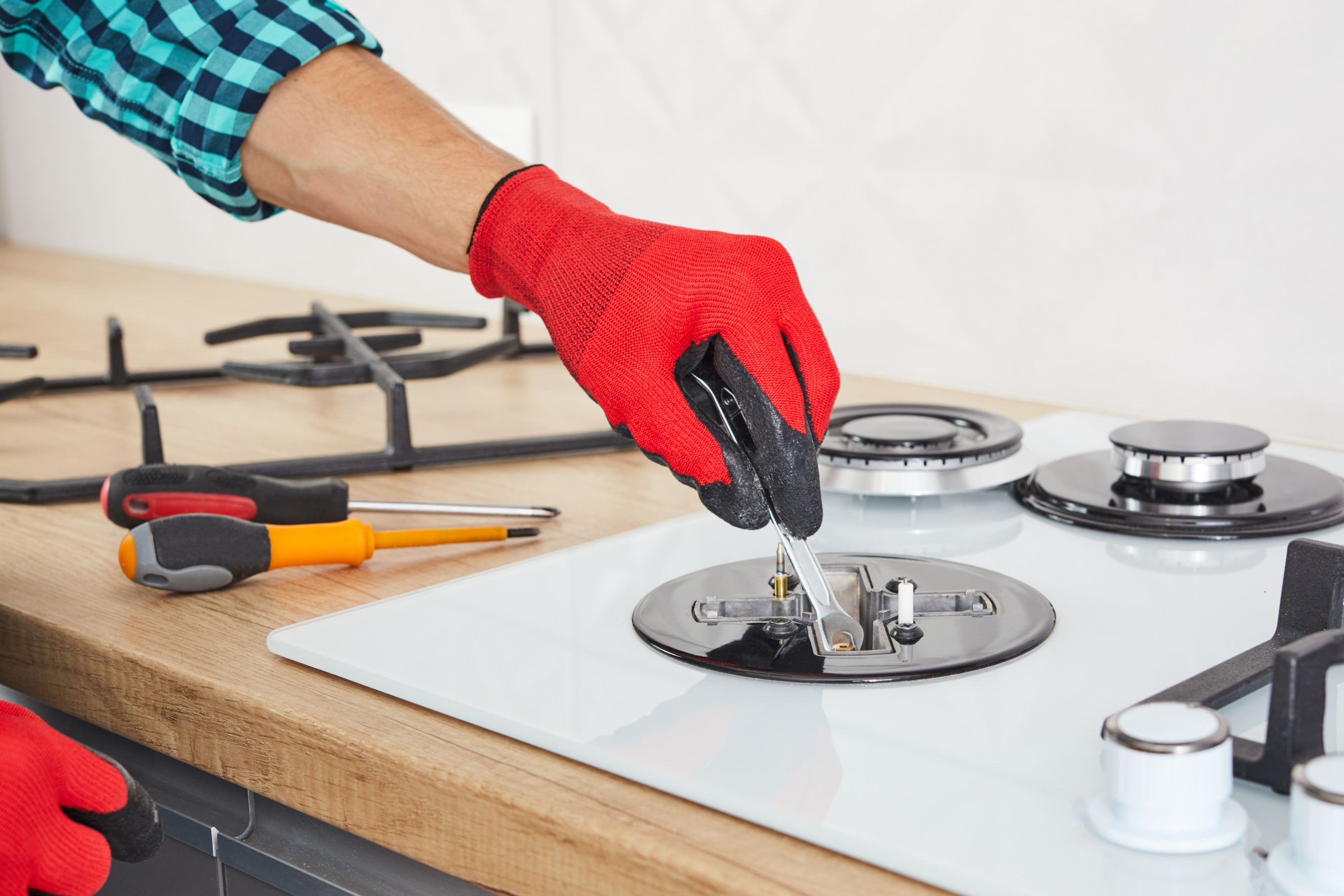 The technician adjusts the burner of a gas stove for cooktop repair.