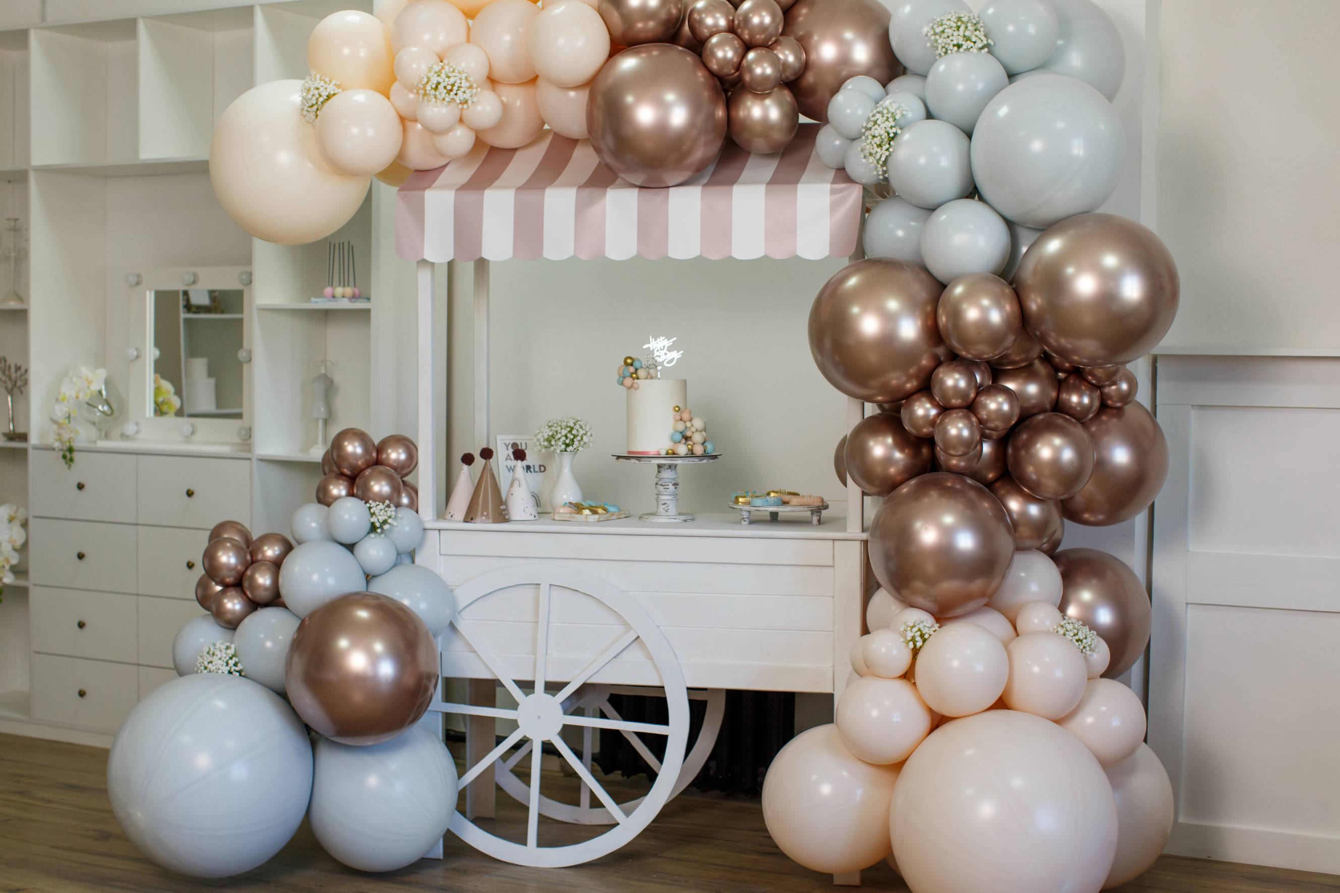 Balloon decoration with a cake on top of a cart for a birthday party.