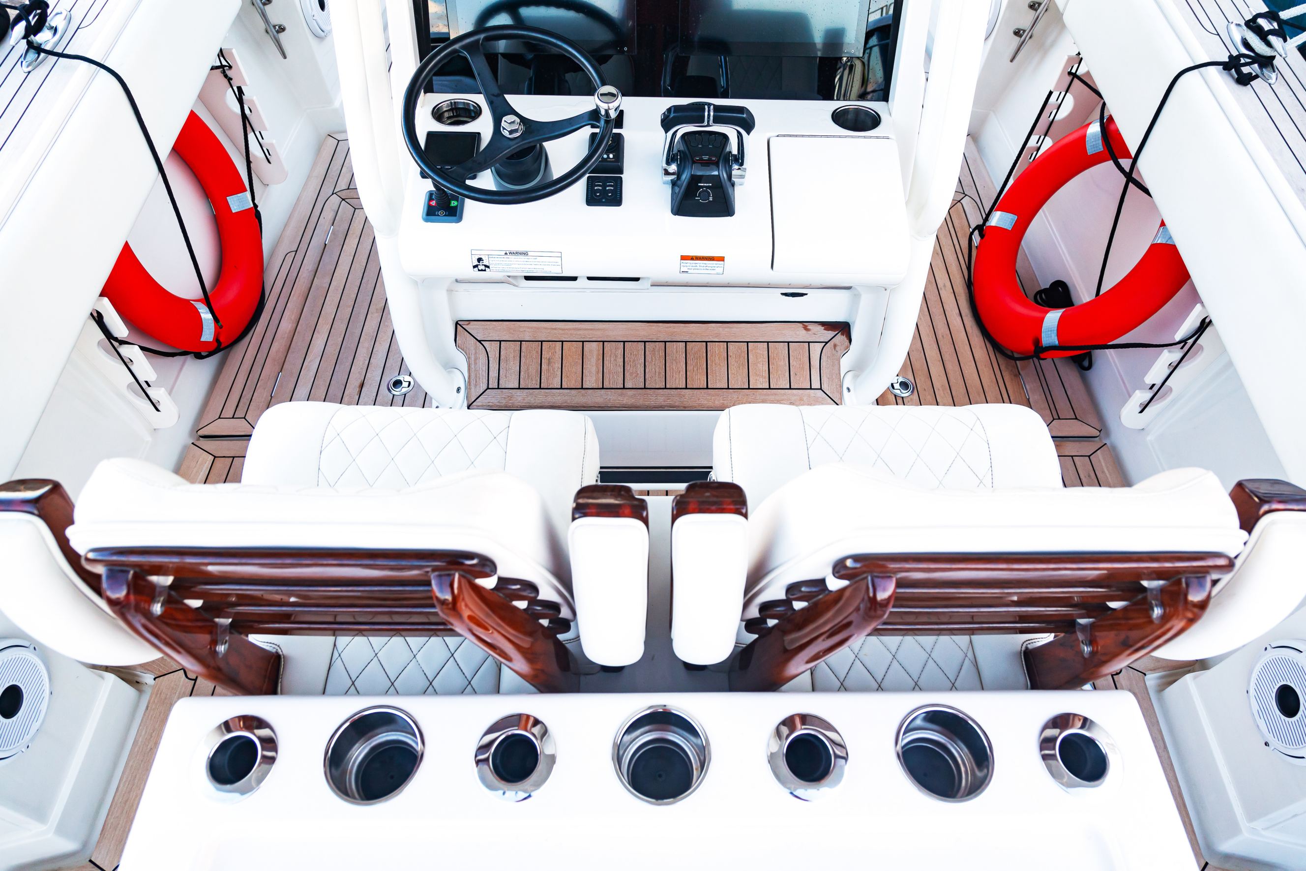 Luxurious boat control cabin with great boat upholstery like white leather seats, steering wheel, gear lever, and on-board computer.