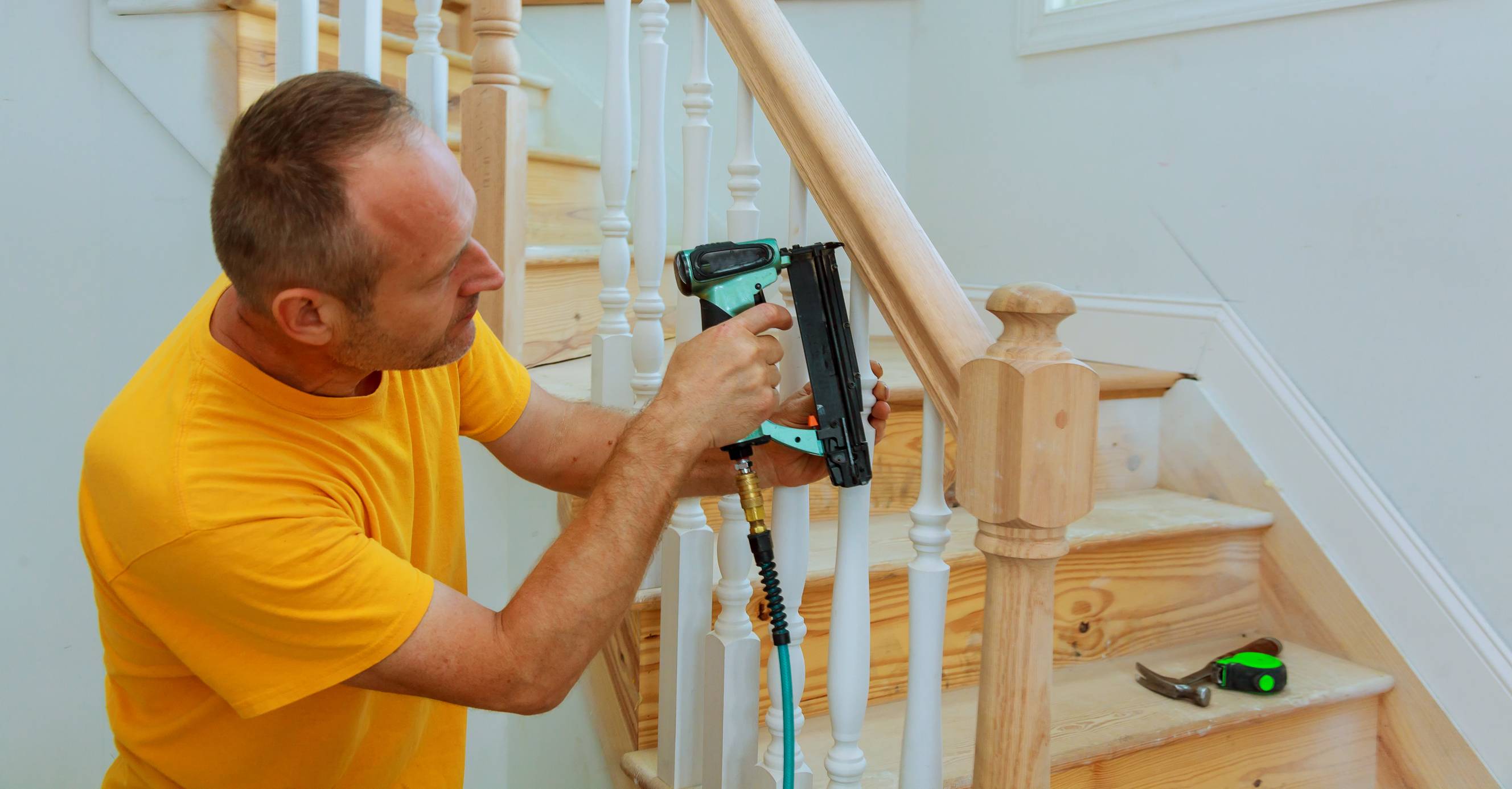 A tradesman installing a wooden balustrade inside a home.