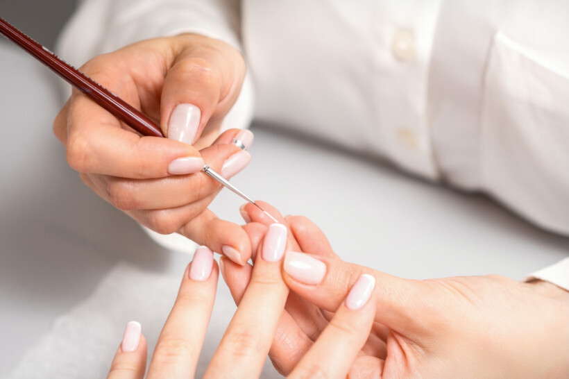 manicure cost - manicurist expertly applying French tips to client's nails