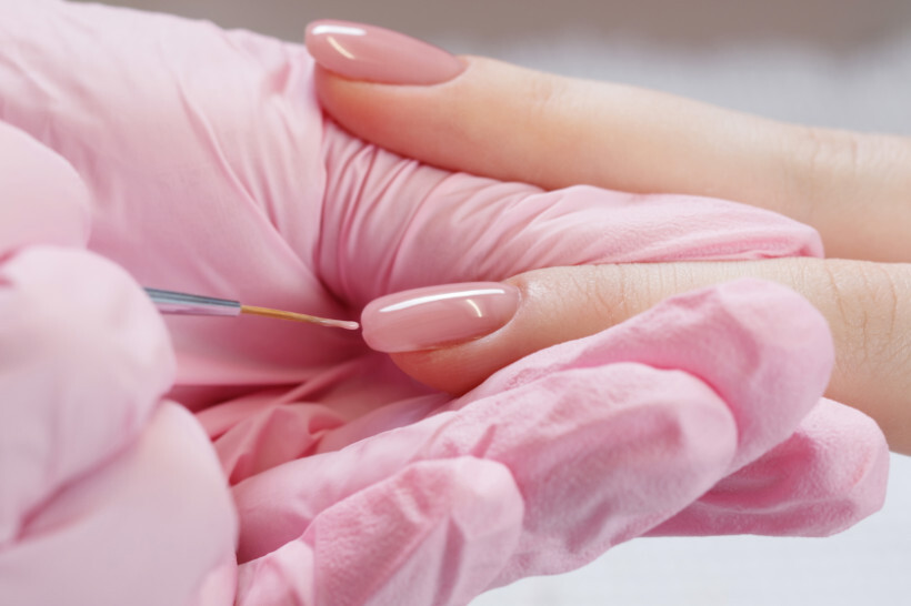 manicure cost - manicurist applies pink nail polish