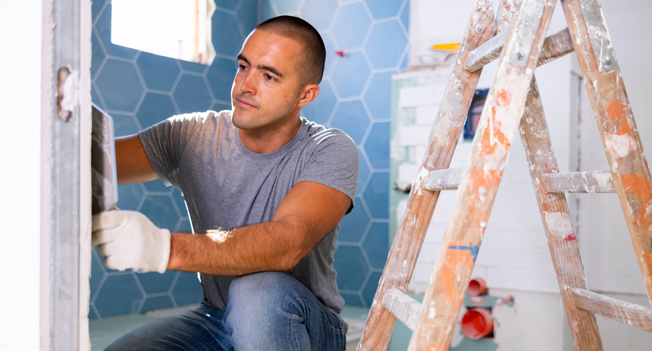 A contractor laying wall tiles for a bathroom renovation project.