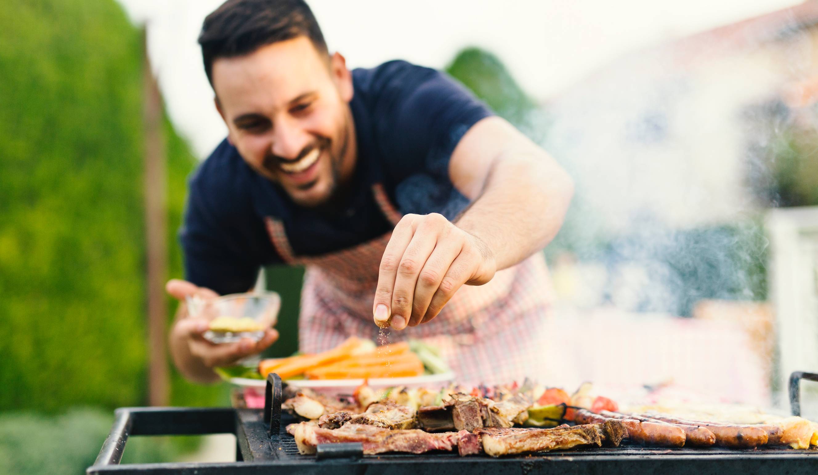 A man helping with bbq catering and grilling meat for a party.