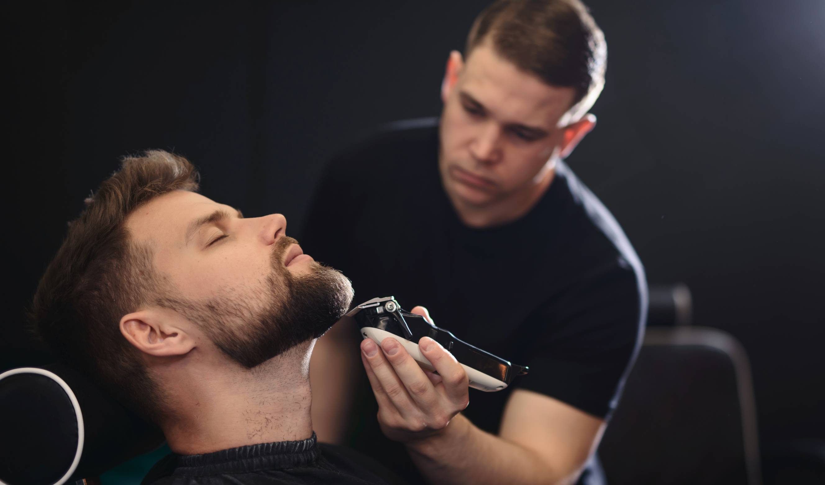 A man getting beard grooming from a local barber in the area.