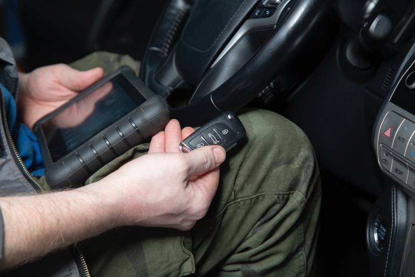 car key replacement cost - a man programming a new car key