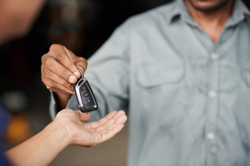 car key replacement - a car locksmith handing out a new car key