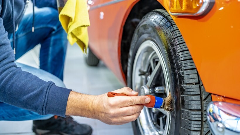 Car detailing vs car wash - A person using a brush to clean a car tyre