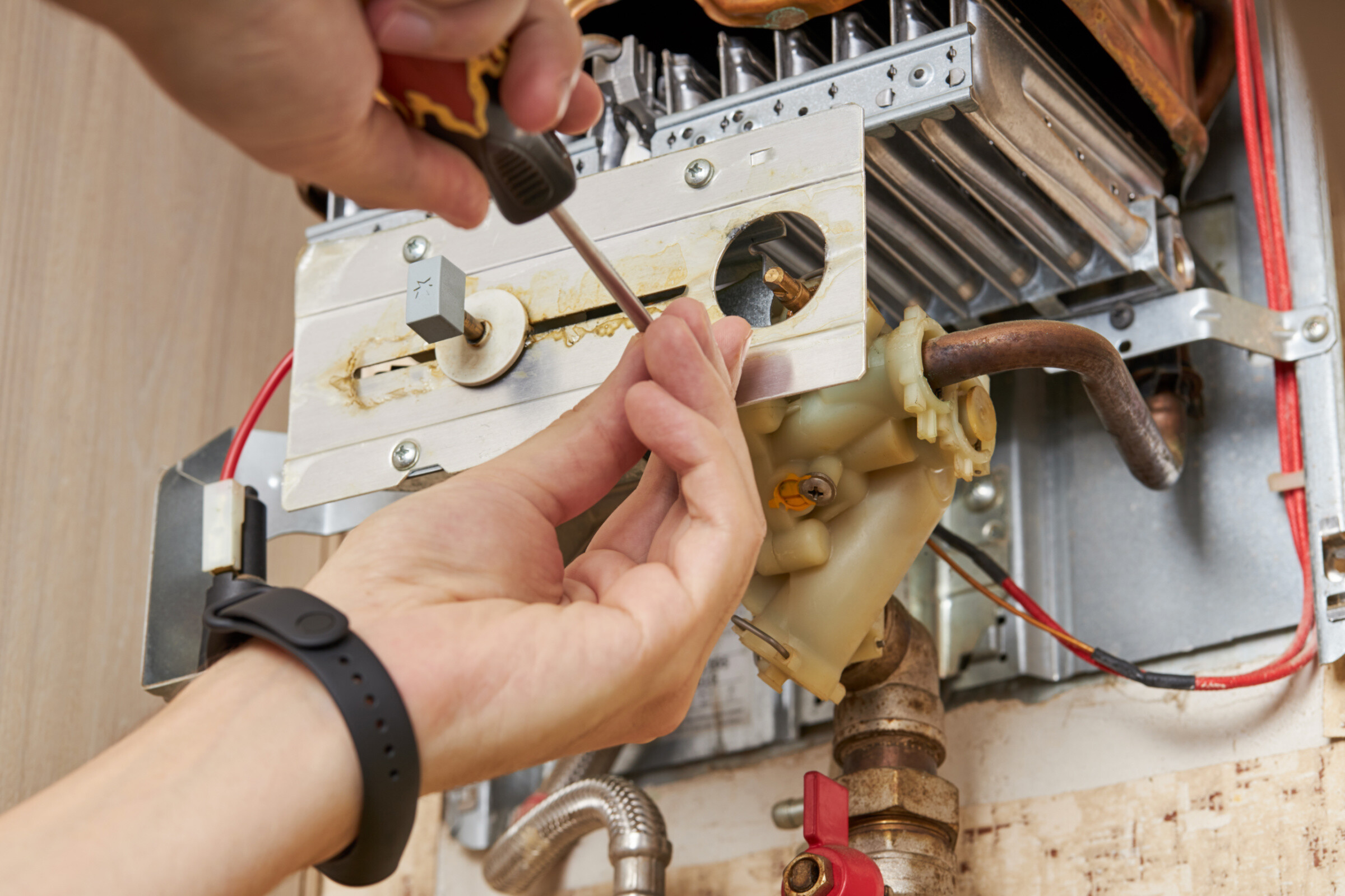 A boiler service technician repairing a boiler indoors.