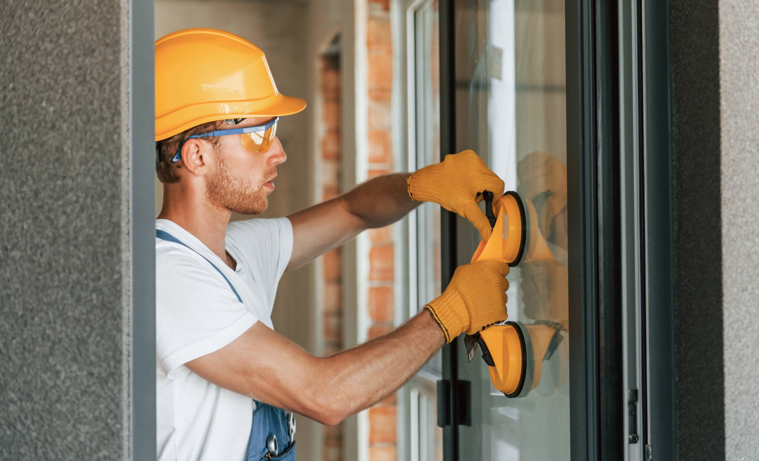 A handyman working on a glass window for an emergency glass repair service.