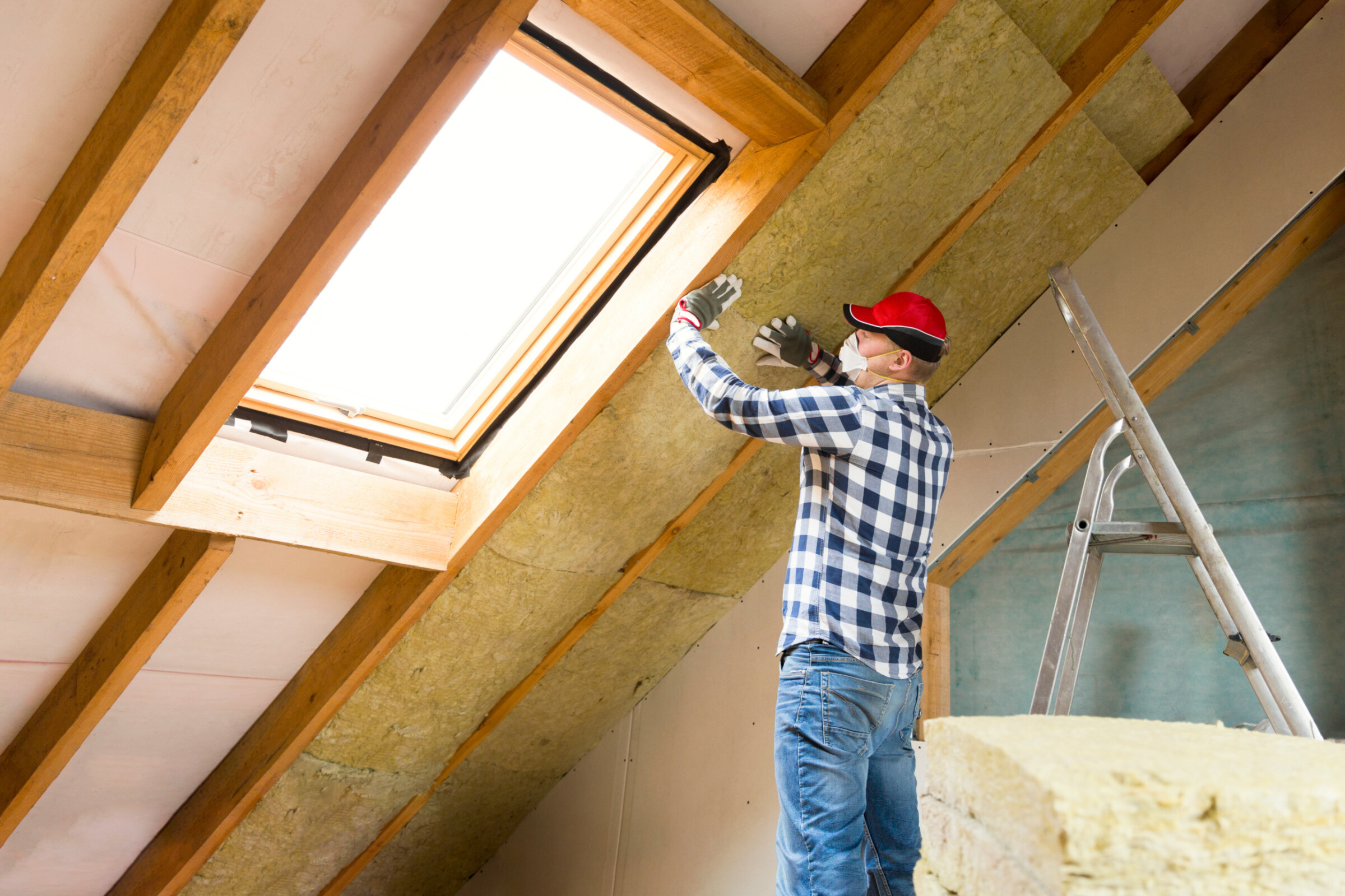 An expert installing insulation in the loft for home renovation.