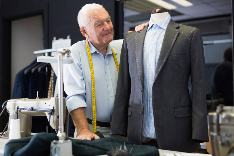 double breasted vs single breasted - Experienced tailor inspecting a single-breasted gray suit jacket on a mannequin