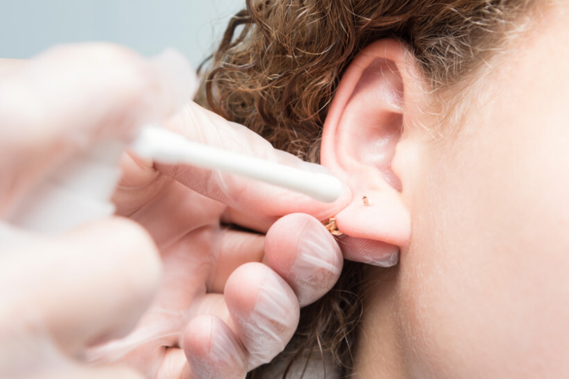 ear piercing cost - woman having her new ear piercing cleaned