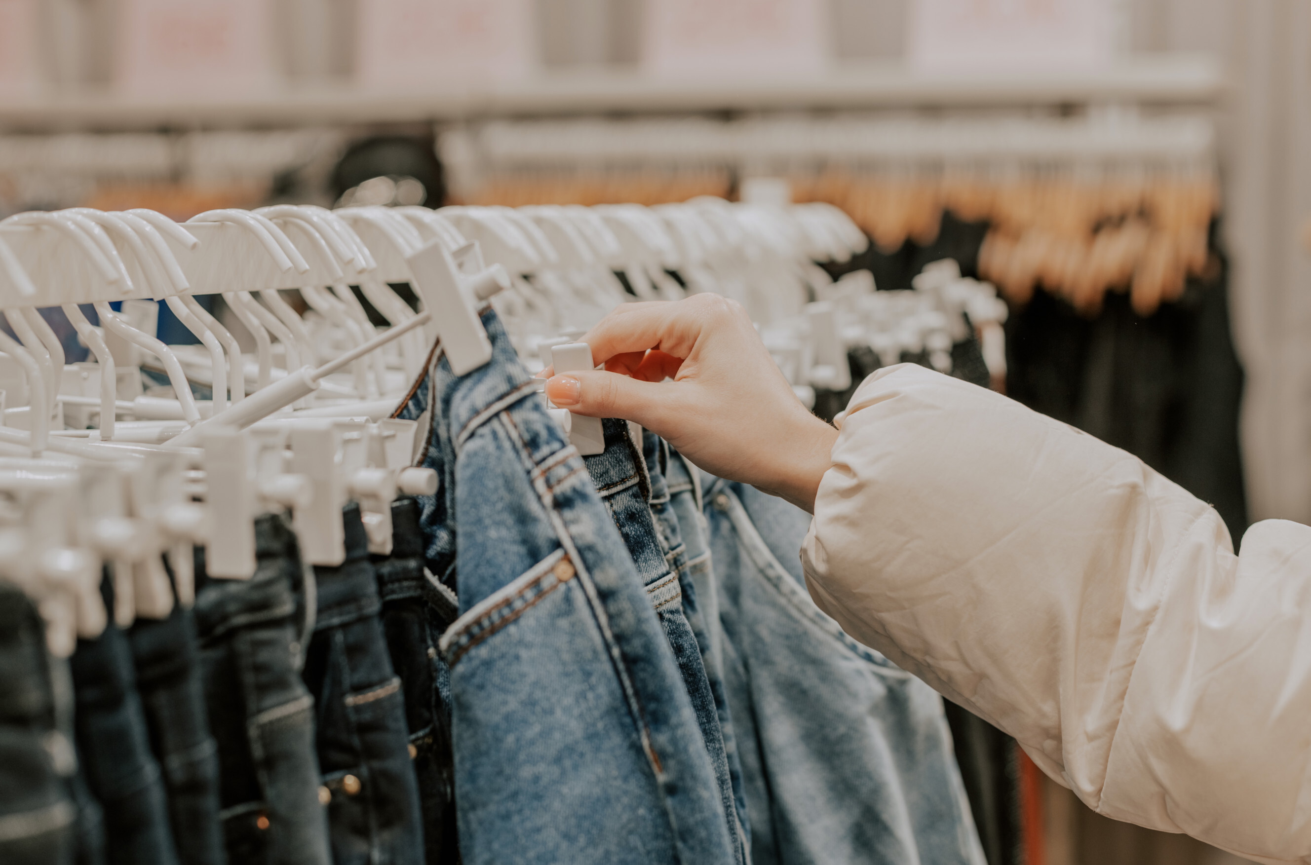 Person selecting jeans from a store rack