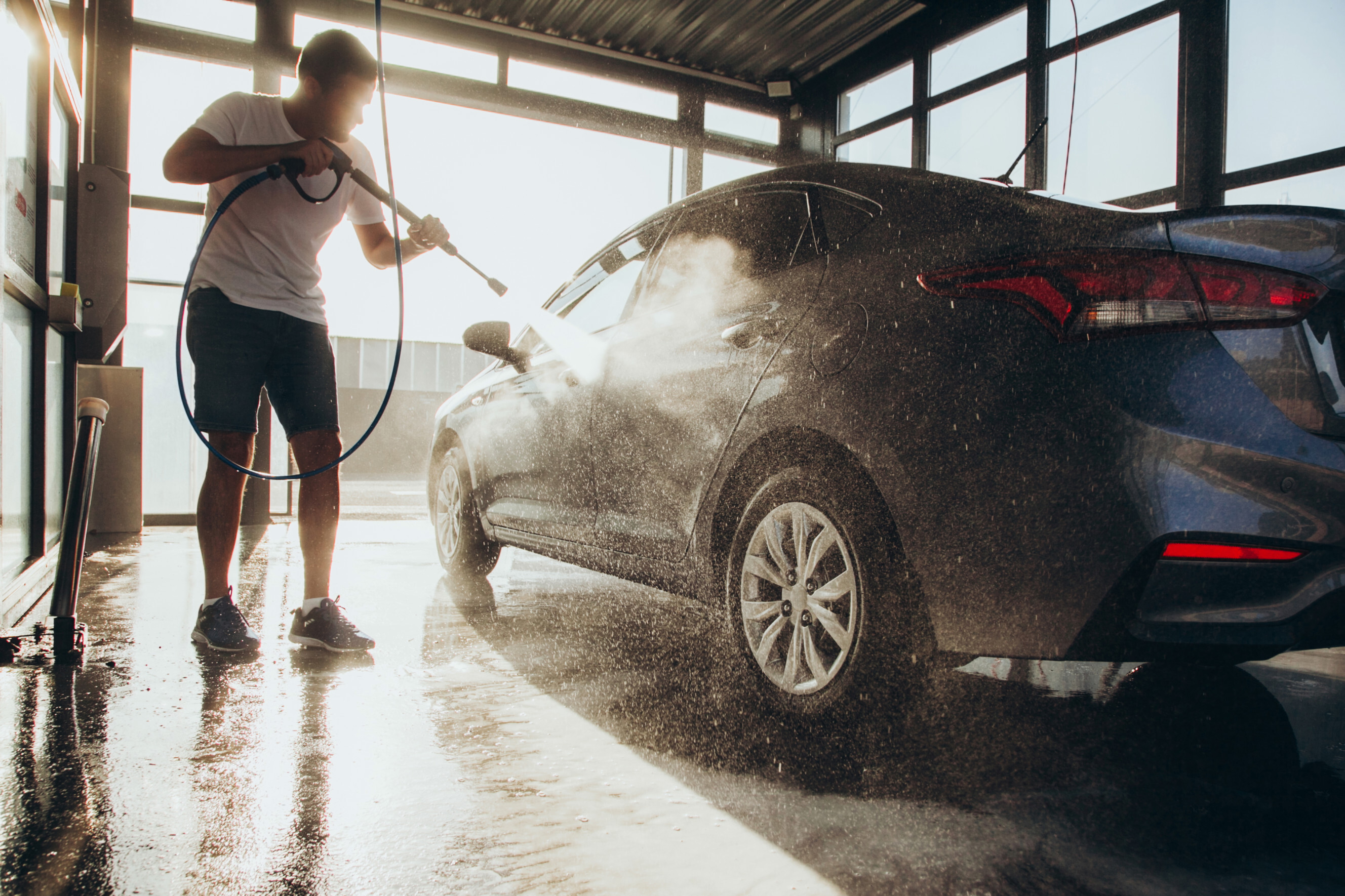 Man washing his car with a hose