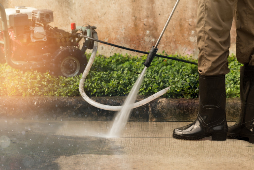 power washer vs pressure washer - Man power washing his driveway