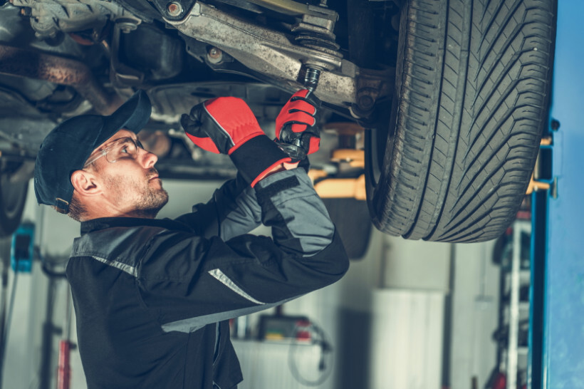 automotive mechanic vs technician - Male mechanic performing repairs under a car