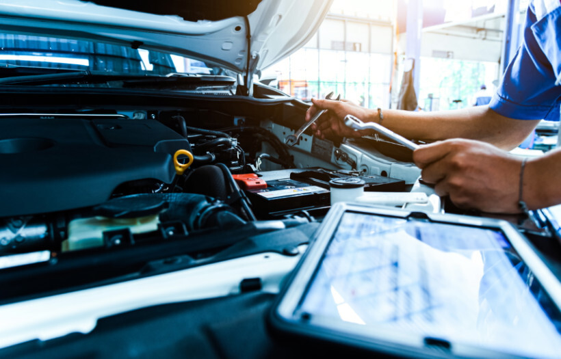 automotive mechanic vs technician - Mechanic inspecting a car engine in a garage