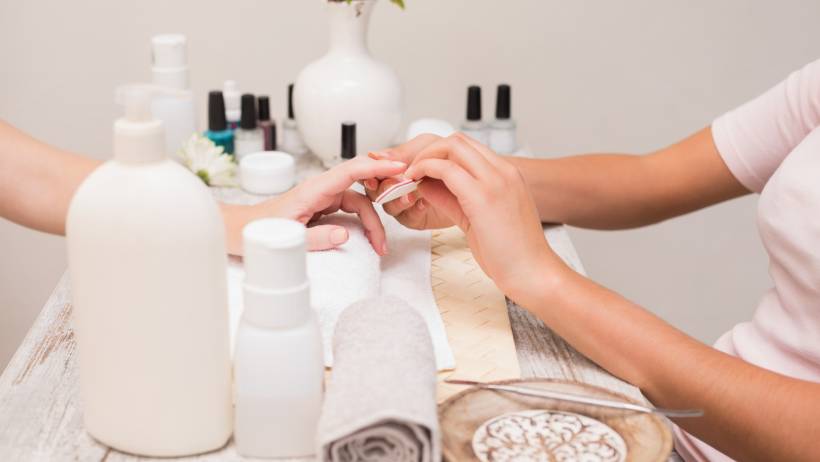 Hands of a nail technician diligently working on a client's nails in a professional salon environment. - nail technician vs manicurist