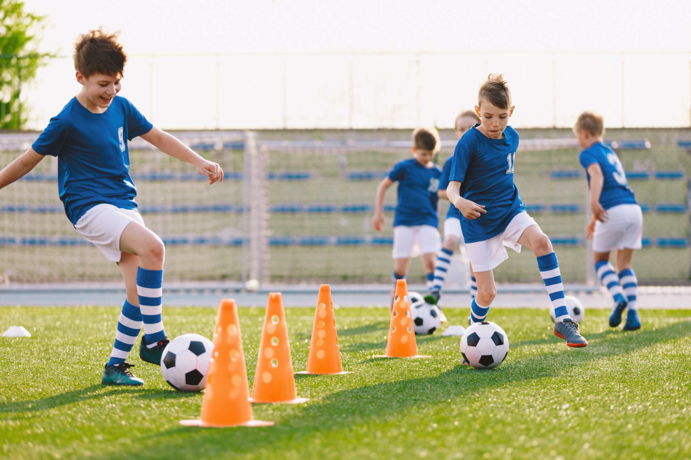 Young soccer player improving dribbling skills on turf football training pitch.