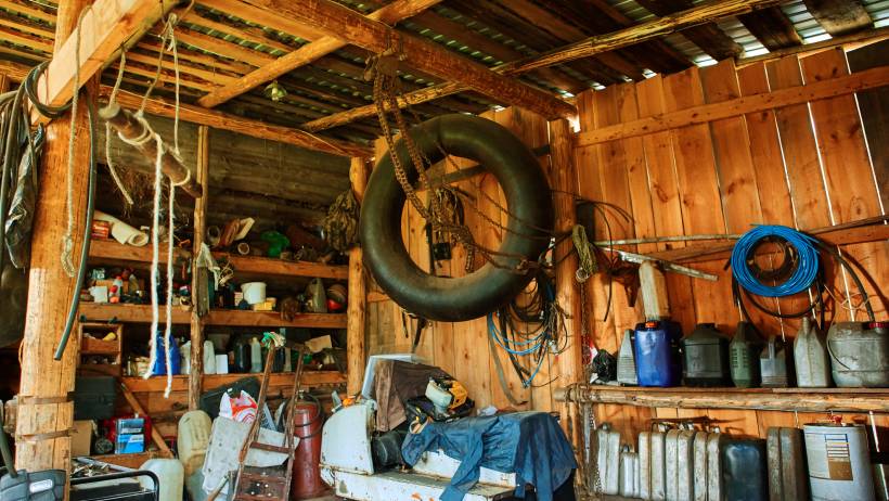 Cluttered and weathered storage shed packed with various tools and equipment - barn vs shed