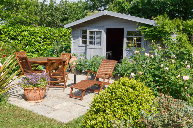 metal vs wood shed - insulated shed in a beautifully landscaped garden with patio furniture