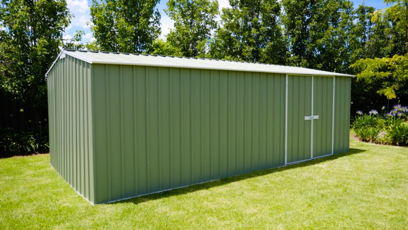 Timber frame shed vs steel shed -  A green steel EasyShed in a backyard, surrounded by lush greenery, demonstrating its rust and termite-resistant construction