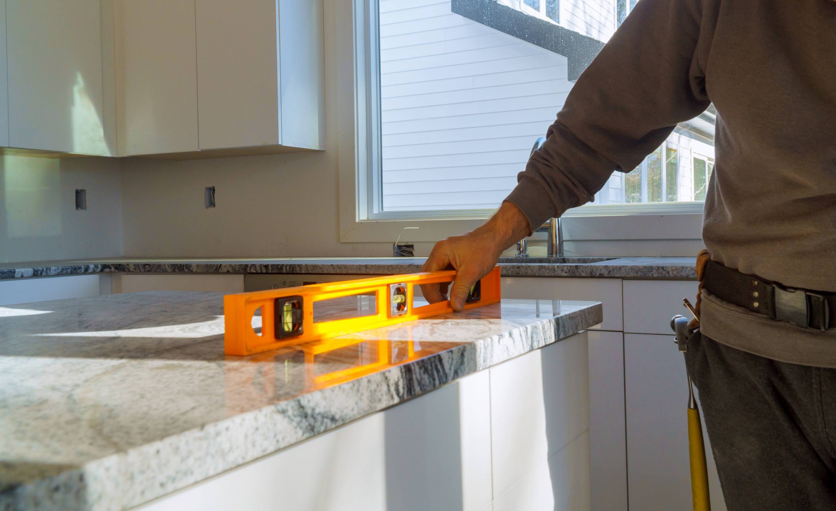 A contractor measuring granite countertop for a kitchen countertop fabrication service