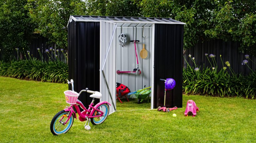 A black and silver EasyShed shed placed on a green lawn