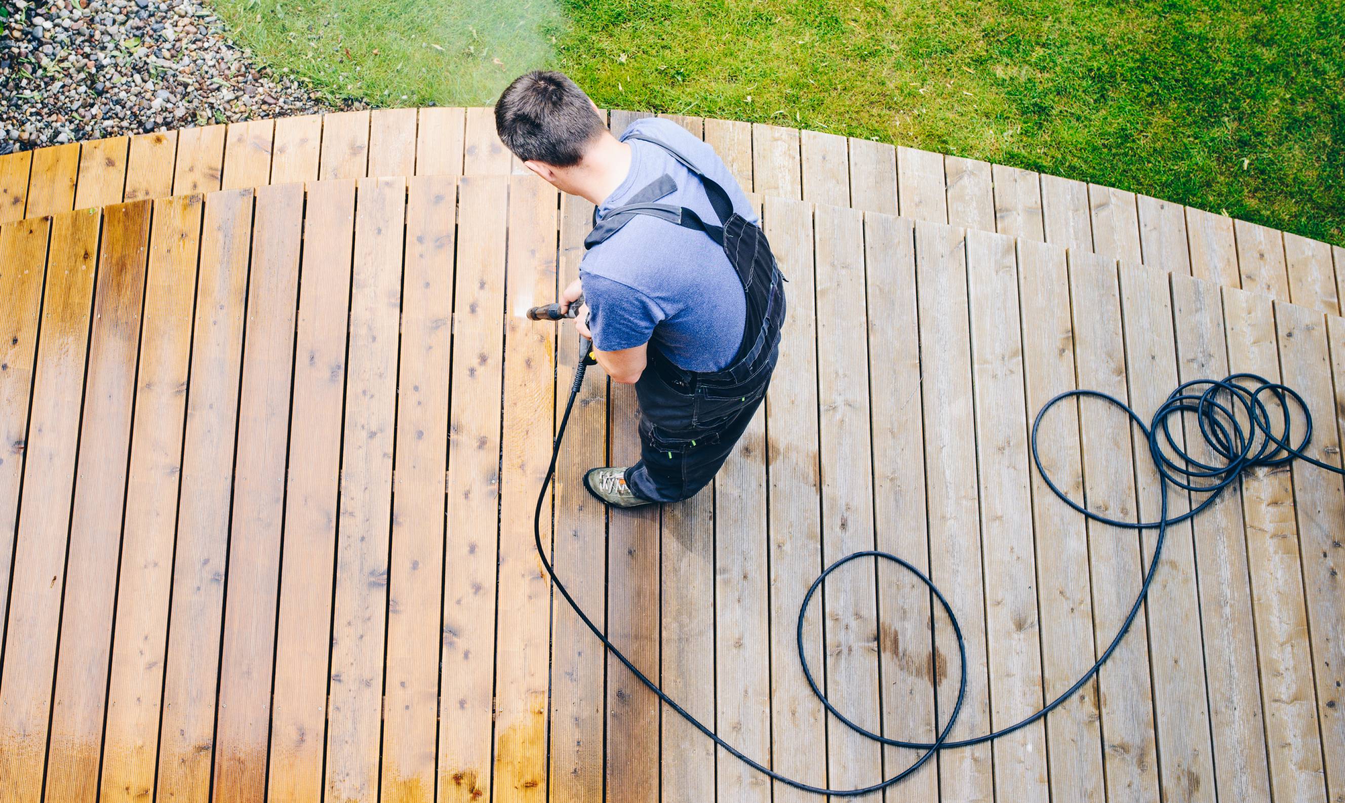 A professional cleaner doing local power washing service on a deck.